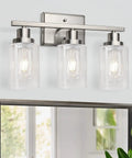 Killer 3 Light Wall Sconces With Clear Glass Shade And Brushed Nickel Finish mounted above a mirror, providing stylish illumination.