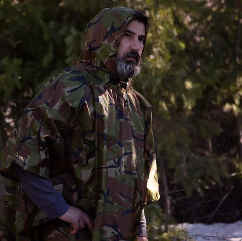 Man wearing Ultra Lightweight Ripstop Nylon Rain Poncho With Adjustable Hood Camouflage Pattern Ultra Packable hiking outdoors.