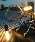Dope Handcrafted Steampunk Water Pipe Robot Desk Lamp With Vintage Industrial Vibe for Bedside, lit in cozy bedroom setting