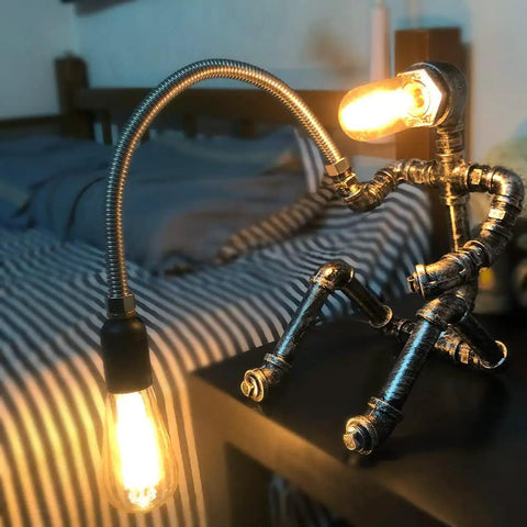 Dope Handcrafted Steampunk Water Pipe Robot Desk Lamp With Vintage Industrial Vibe for Bedside, lit in cozy bedroom setting