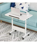 Mobile Workstation Lap Desk With Height Adjustable Wheels And Non Slip Bezel Edge Rolling Computer Table For Breakfast In Bed on a couch with a laptop.