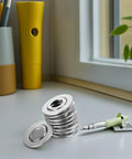 30 Pcs Stainless Steel Fire Sprinkler Cover Plates With Slick Silver Dual Disc Design on a countertop next to a pen and plant.