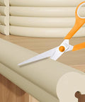 Edge Corner Protector Self Adhesive Foam Bumper Guard For Furniture 78.7 Inch NBR Cushion cut by scissors on a wooden surface.