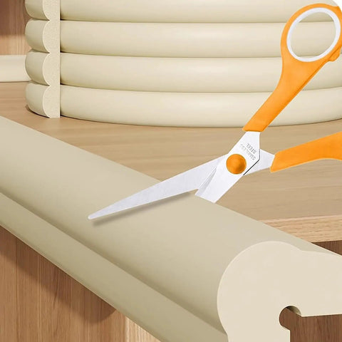 Edge Corner Protector Self Adhesive Foam Bumper Guard For Furniture 78.7 Inch NBR Cushion cut by scissors on a wooden surface.