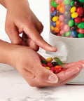 Stay Stocked On Your Favorite Treats Triple Compartment Candy Vending Machine Dispenser Pearl White, hands dispensing colorful candy.