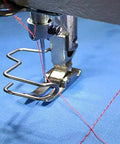 Close-up of a Six Pack Universal Iron Finger Guard installed on a sewing machine foot, protecting fingers while crafting.