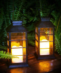 Two Pack Lit Solar Powered Outdoor Hanging Lanterns With Waterproof LED Flickering Flameless Candles in garden at night