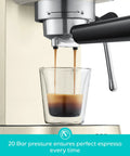 Next Level Compact Espresso Maker With High Pressure Pump And Hassle Free Milk Frother For Pulling Bold Coffee Shots And Topping Off Sweet Lattes Anytime, espresso being brewed into a clear glass shot.