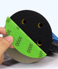 Hand holding a 5 inch 3000 grit hook and loop sanding disc from 50 Piece 5 Inch Hook And Loop Sanding Disc Set With Grits 3000 4000 5000 7000 And 10000 Extra Fine Wet And Dry Sandpaper For Orbital Sander Auto Wood And Metal Polishing, attached to an orbital sander