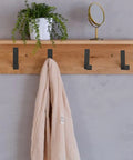 Rugged Heavy Duty Stainless Steel Coat Hook Wall Hanger with a beige coat on a wooden shelf, plant and mirror above