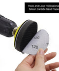 Close-up of Three Inch Sanding Discs Kit piece with hook and loop backing in use, silicon carbide material shown holding by hands.