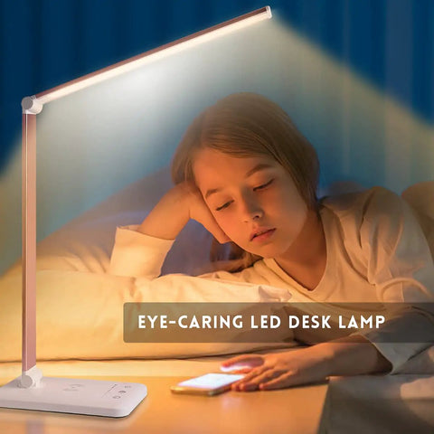 Child reading under Game Changing LED Desk Lamp With Wireless Charger And USB Port, Dimmable Eye Caring Reading Light, Pink