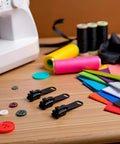 12 Piece Black Zipper Repair Kit With Removable Sliders For Quick Fix On Clothes, Backpacks And Jackets on sewing table