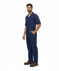 Essential Men's Short Sleeve Zip Up Coverall in Navy Blue, durable poly cotton blend, worn by a man standing.