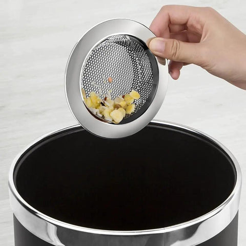 Hand holding 2 Pack Kitchen Sink Strainer Basket Rust Resistant Stainless Steel over a drain with food scraps.
