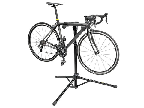 Elite Bike Repair Stand With Built In Parts Bin Stable Tripod Design 360 Degree Rotating Clamp Head Non Marking Rubber Jaws For A Secure Hold Easy Fold Travel Ready Pro Grade Stand For Quick At Home Or Shop Tune Ups holding a bike