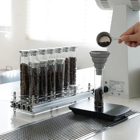 Single Dose Coffee Bean Storage Tubes, Glass And Aluminum Vials, Fourteen Piece Set With Acrylic Board on kitchen counter.