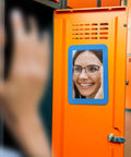 Magnetic Real Glass Mirror 5x7 Inch White Framed Locker Accessory on an orange locker showing a reflection of a woman's face.