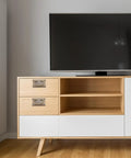 Mid-century modern cabinet with set of four vintage metal drawer pull handles placed on light wood drawers next to TV stand.