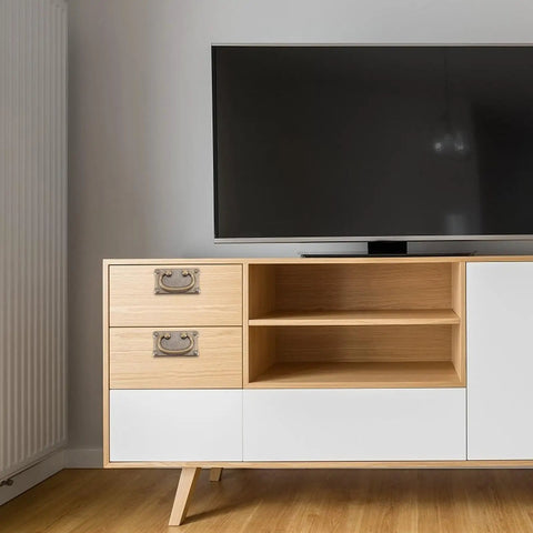 Mid-century modern cabinet with set of four vintage metal drawer pull handles placed on light wood drawers next to TV stand.