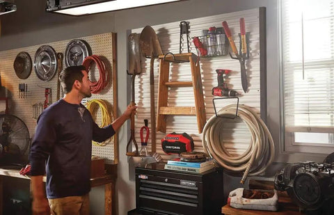 Man organizing tools on VersaTrack Garage Storage Rail With Twenty Piece Mounting Accessories for Drywall Studs and Masonry Pegboard Ready