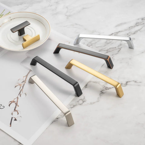 Various styles of cabinet pulls in different finishes on marble surface, including 10 Pack 5 Inch Oil Rubbed Bronze Cabinet Pulls Set For Kitchen Cabinets Drawers.