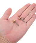 Two solid brass upholstery tacks with 1/2 inch heads in a hand, ideal for furniture projects and home decor fixes.