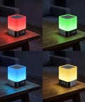 Four color variations of Five In One Night Light Bluetooth Speaker Alarm Clock MP3 Player with multi-color LED lamp on table.