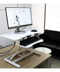 Stylish White Standing Desk Converter With Smooth Gas Spring Lift For Laptop Or Monitor on a wooden table with a monitor and keyboard.