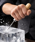 Heavy Duty Ice Pick With Safety Cover in use, metal tip shattering block ice, wooden handle grip.