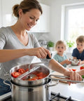 Woman using Stainless Steel Food Mill With Three Milling Discs on pot for tomato sauce, children in background