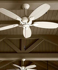 Ceiling fan with five white blades, viewed from below in a wooden interior setting.