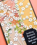 Handmade card with floral paper, die cut white flowers, and black tag reading 'looking forward to your best year ever'