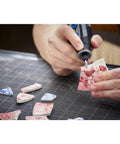 Dremel 729-01 engraving accessory micro kit; hand-held rotary tool engraving a tile; several floral tile fragments on mat.
