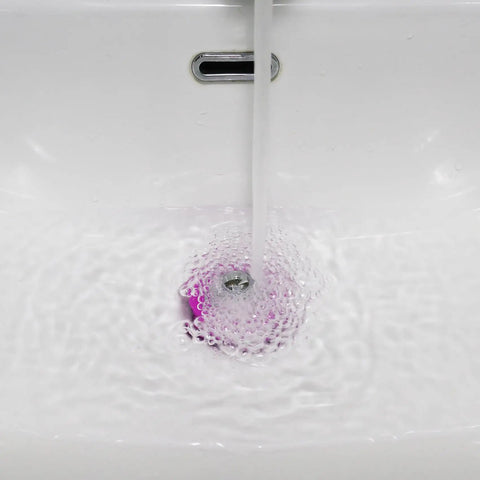 Water flowing into a sink with a Pink Silicone Bathtub Stopper With Chrome Plated Handle for effective drainage.