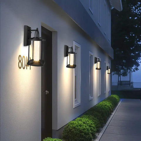 Dusk To Dawn Outdoor Light With Crystal Glass Drops, LED Porch Sconce In Matte Black illuminating house exterior at night