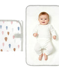 Portable Baby Changing Pad With Waterproof, Wipeable Surface For On The Go Parents; baby lying on unfolded mat, folded pad shown