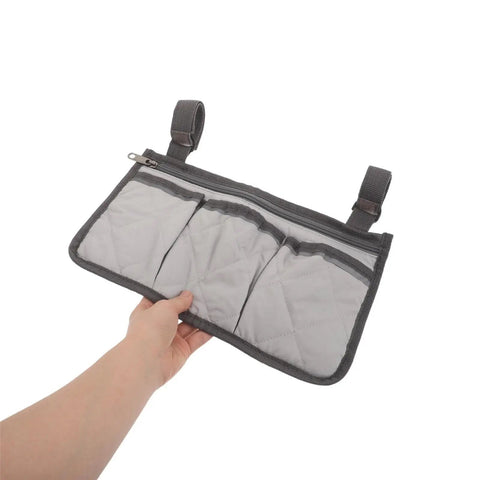 Hand holding grey Bed Rail Hanging Organizer With Four Pockets For Bedside Essentials Grab And Go Caregiver Friendly Storage Pouch