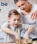 Mother and daughter baking together in a kitchen, mixing ingredients in a bowl on a counter with eggs and flour.