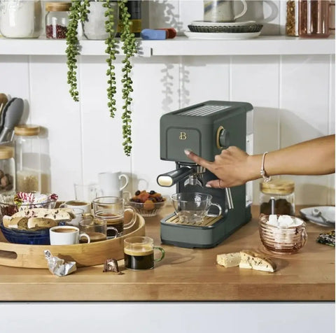 Rock Solid Compact Espresso Machine In Fresh Thyme Green with a 20 bar pump, on a kitchen counter, surrounded by coffee and snacks.