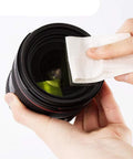 Lens cleaning paper, 4x3 inch lint-free tissue used to wipe a camera lens.