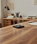 Cradle Balance Pendulum Balls Set With Black Base on a desk in an office setting, showcasing kinetic motion for stress relief and learning.