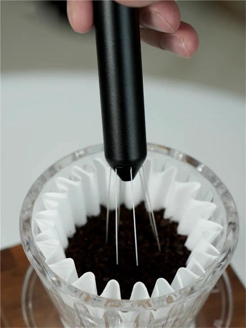 No Fuss WDT Needle Tool For Espresso Brewing retractable stirrer in use over coffee grounds in a filter.