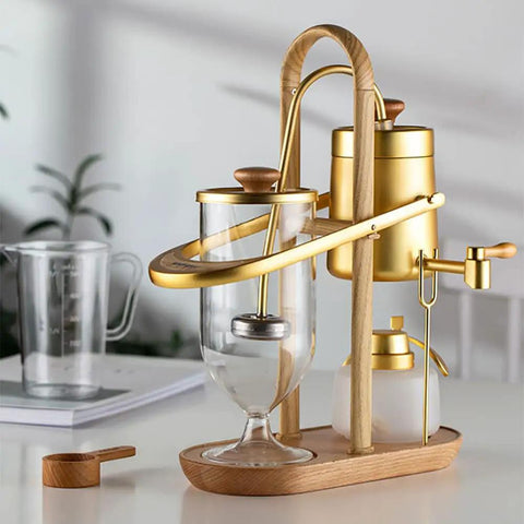 Top Shelf Belgian Siphon Coffee Maker With Stunning Gold Finish Built From Heavy Glass And Steel Frame Relies On Steam Heat And Gravity Action To Pull Silky Smooth Brews Fast Sick Flex For True Coffee Geeks Wanting Elite Taste At Home Or Work - Manual brewer with gold and glass design.