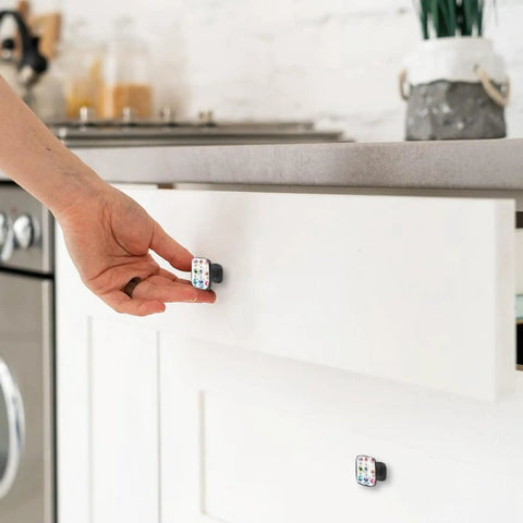 Person holding 4 Pack Colorful Mushroom Watercolor Cabinet Knobs with Crystal Glass Tops and Black ABS Backing on white drawer.
