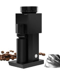 Badass Electric Coffee Grinder With 150 Tight Adjustments, Slick Stainless Steel Housing, And Knockout Uniform Grind For Espresso Pour Over And French Press In Matte Black next to coffee beans and metal blade.