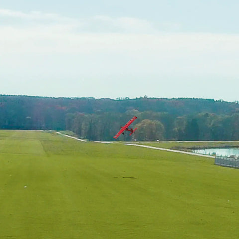 A red RC plane flies over a green field in Evolution RC Flight Simulator Software Only With Dope VR Headset Support Air And Heli.