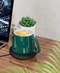 Badass Portable Cup Warmer And Coffee Mug Heating Coaster Offering Smart Thermostatic Temperature Control for a green mug on a desk