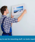 Man using Heavy Duty Interlocking Reclosable Fastener Tape 1in by 2in Set of 10, High Temp 93C to mount picture frame on wall.