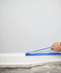 Applying ProGrade Painter Tape With PaintBlock Technology Blue 1.5 Inch Wide Multi Surface Masking Tape along a white baseboard